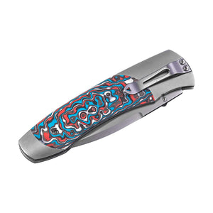 Closed folding pocket knife with gray metal frame, blue-red patterned handle scales and a pocket clip.