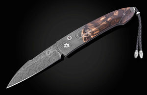 A Damascus steel folding pocket knife with a patterned steel blade and a brown wood-grain handle, shown diagonally on a dark background with a black cord lanyard.