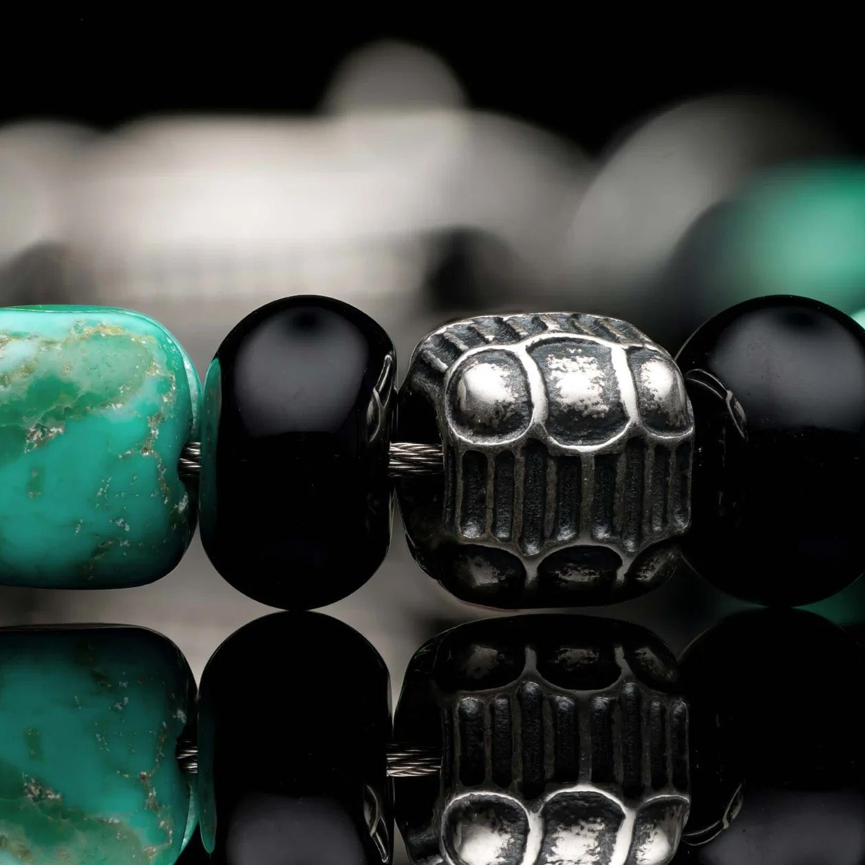 Close up of William Henry Shadowline bracelet with turquoise, black onyx, and sterling silver beads on black background