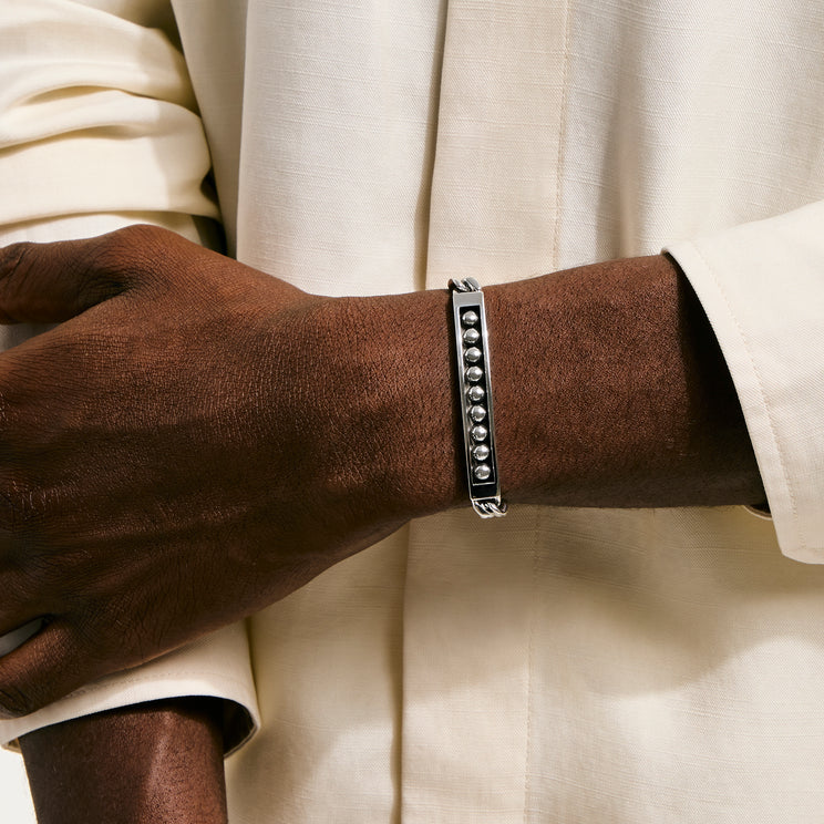 Silver bracelet on a wrist with a neutral background