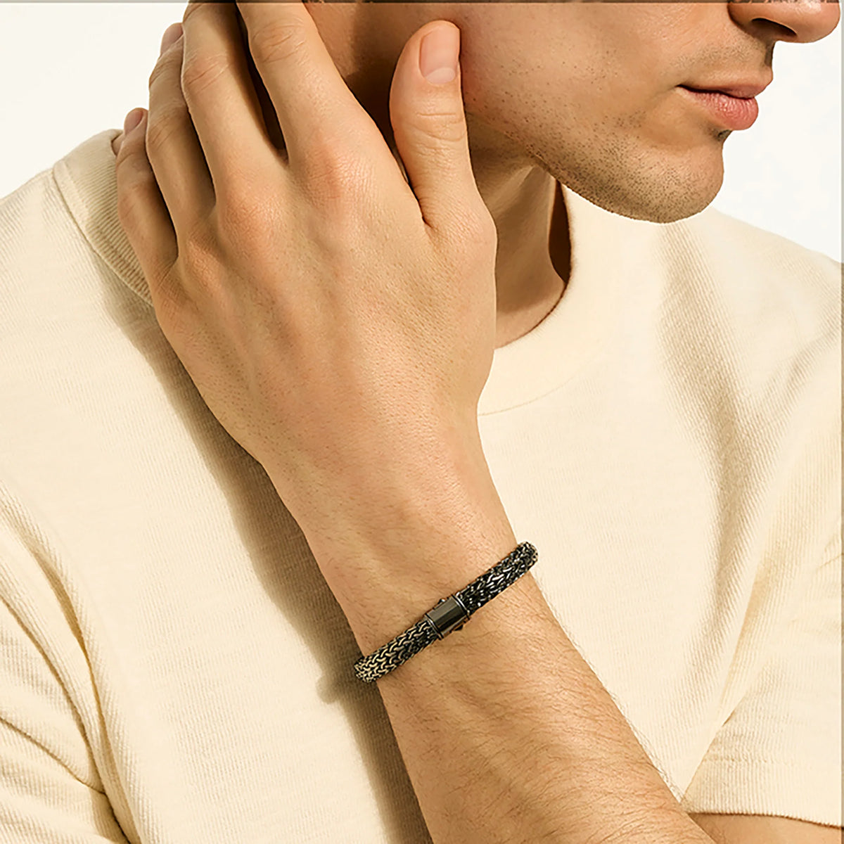 Man wearing a black braided bracelet on a plain background