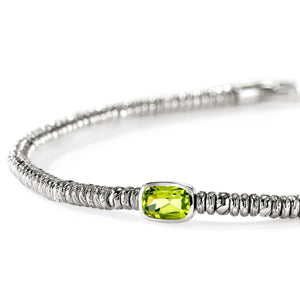 A silver-toned beaded bracelet featuring a central bezel-set rectangular green peridot gemstone, photographed on a clean white background.