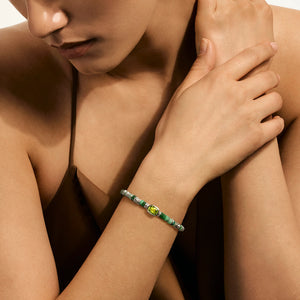 Close-up of a person wearing a turquoise bracelet on a neutral background