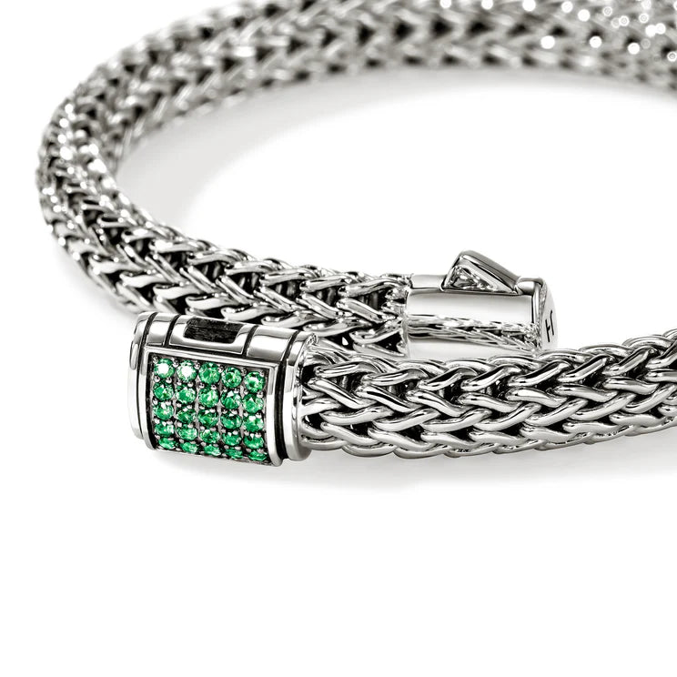 Silver braided bracelet with a emerald gemstones clasp on a white background