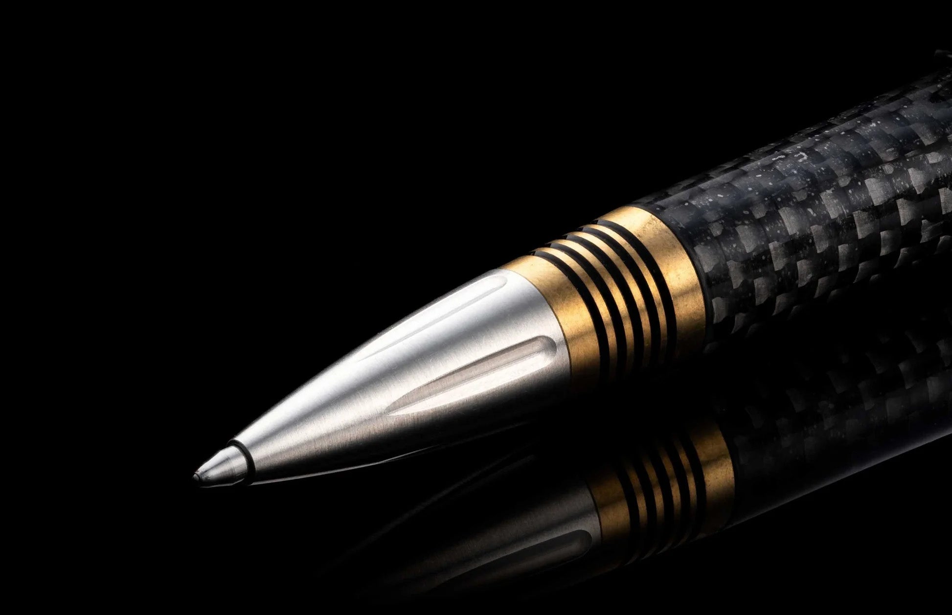 Close-up of Caribe 15 pen showing stainless steel tip, brass spacer rings and carbon-fiber barrel on black background