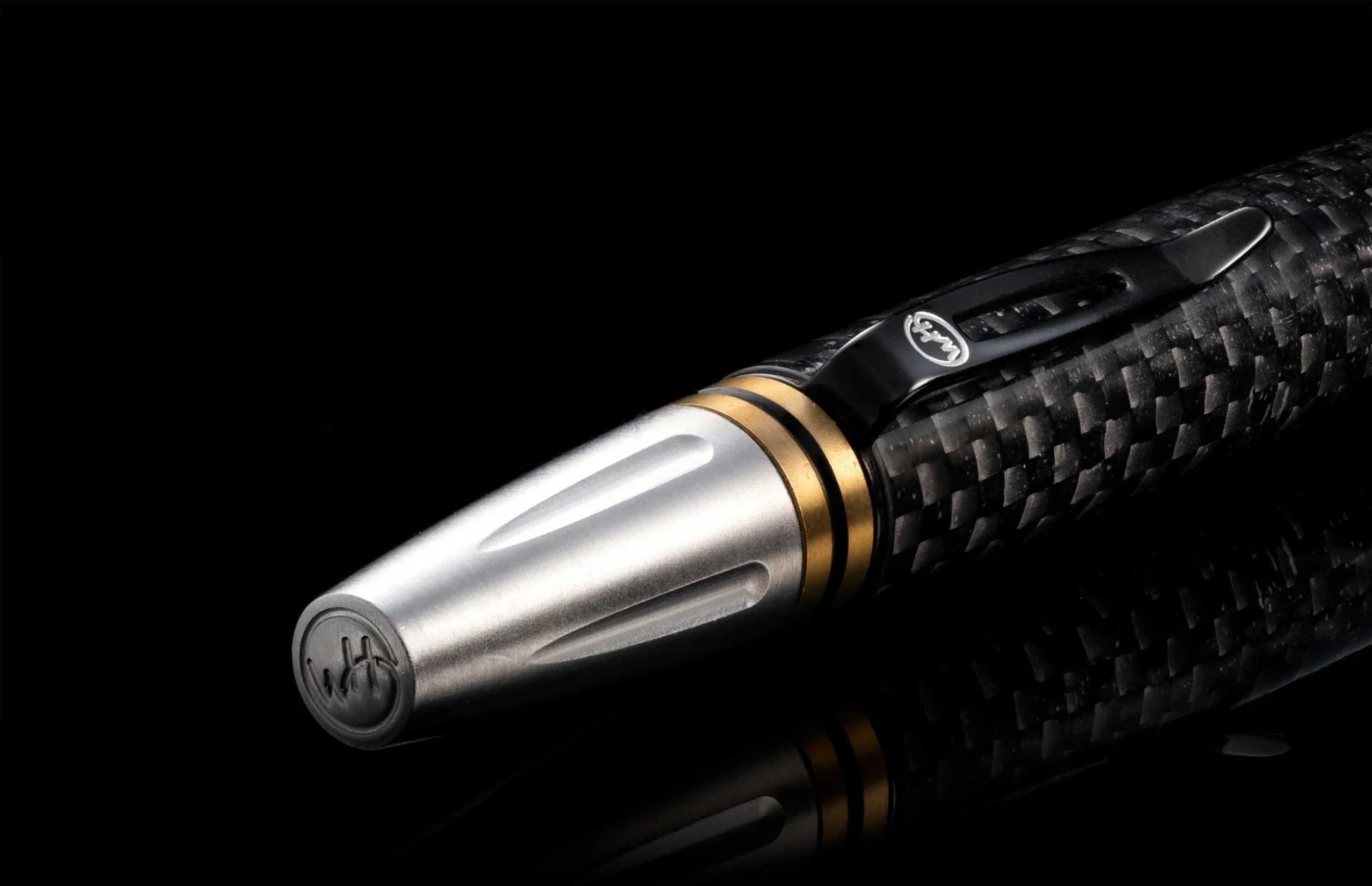 Angled close-up of Caribe 15 pen showcasing carbon fiber barrel, brass spacers and stainless tip on black background
