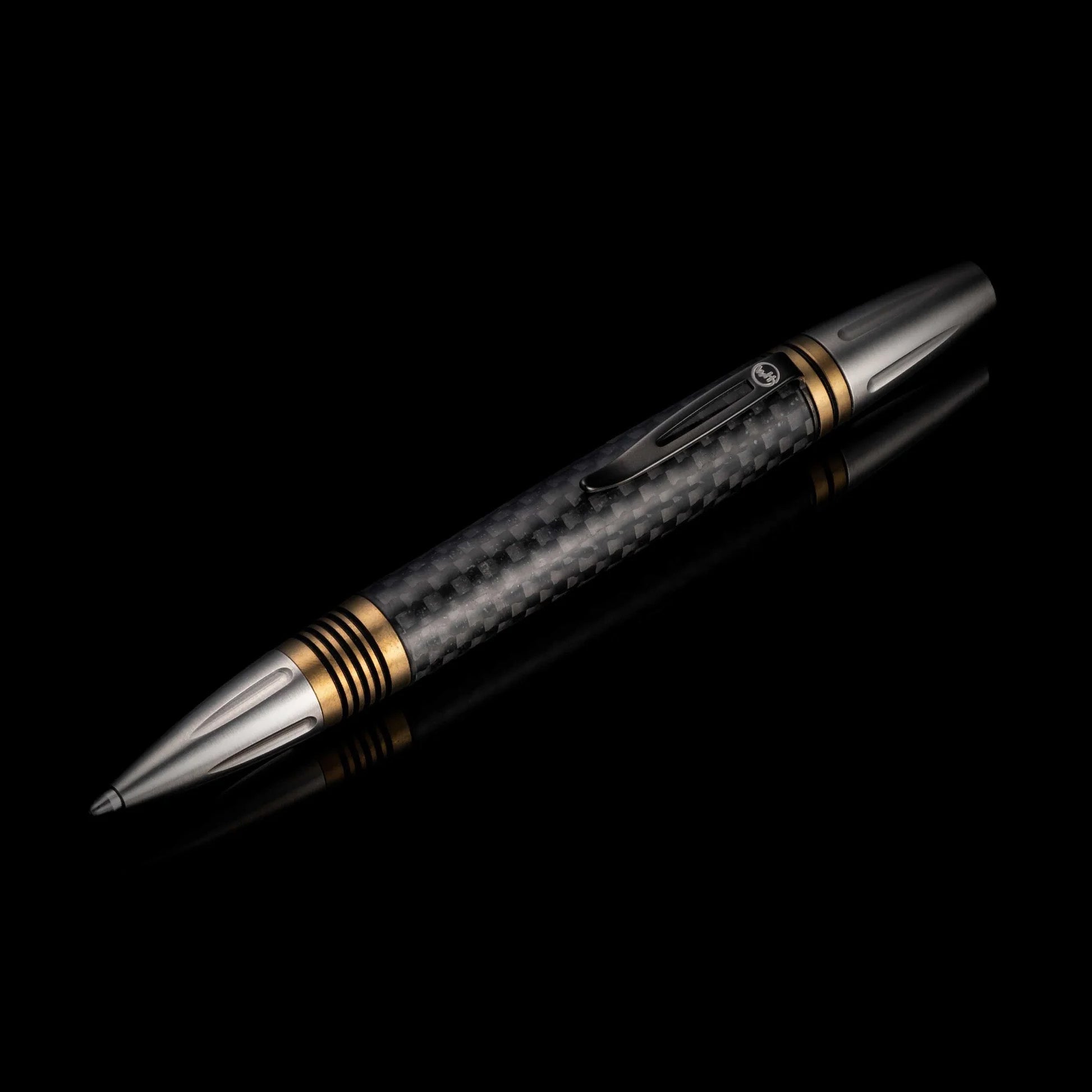 Diagonal view of William Henry Caribe 15 pen showcasing carbon fiber barrel and brass spacers on black reflective background
