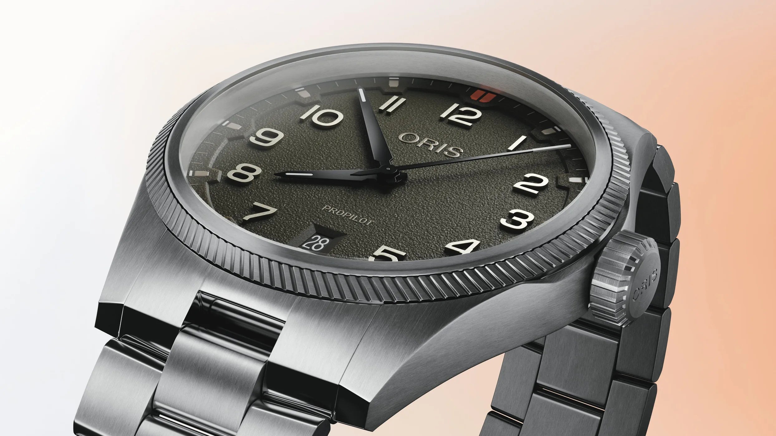 Oris watch with a dark green and silver bracelet on a gradient background