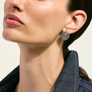 Close-up of a woman wearing a silver earring with a textured design.