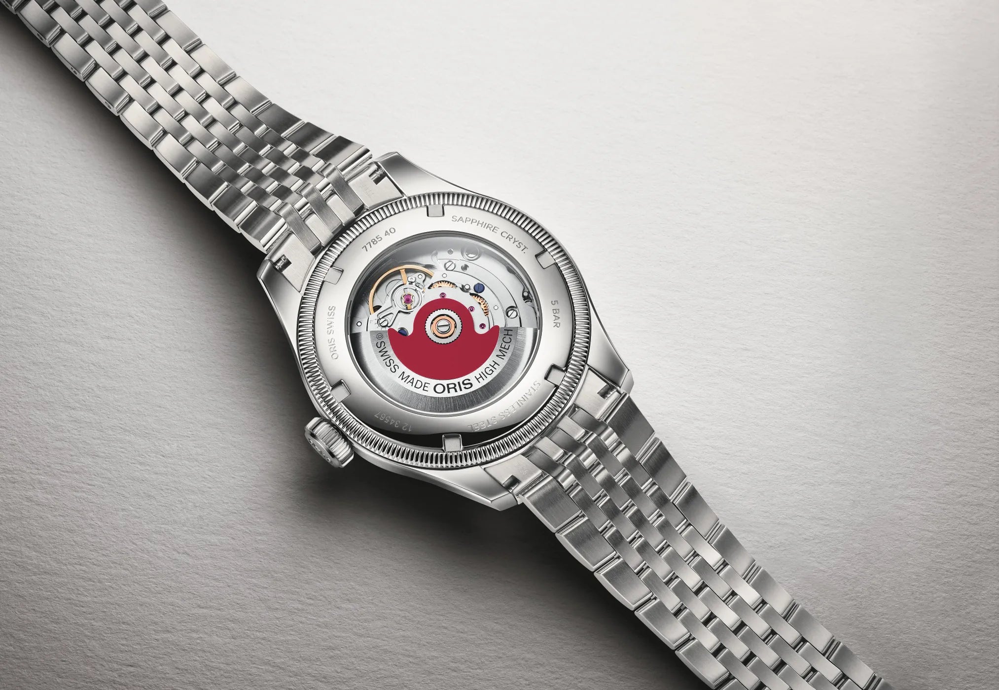 Caseback of a silver watch with on a gray background