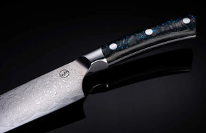 Close-up of Kultro Pro chef knife showing Damascus blade pattern and blue-speckled maple handle on black background