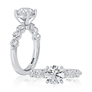 Top and side views of seven-stone engagement ring with round center in six-prong setting and side diamonds on white