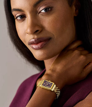 Woman wearing 18K gold‑plated rectangular watch with purple dial and Roman numerals