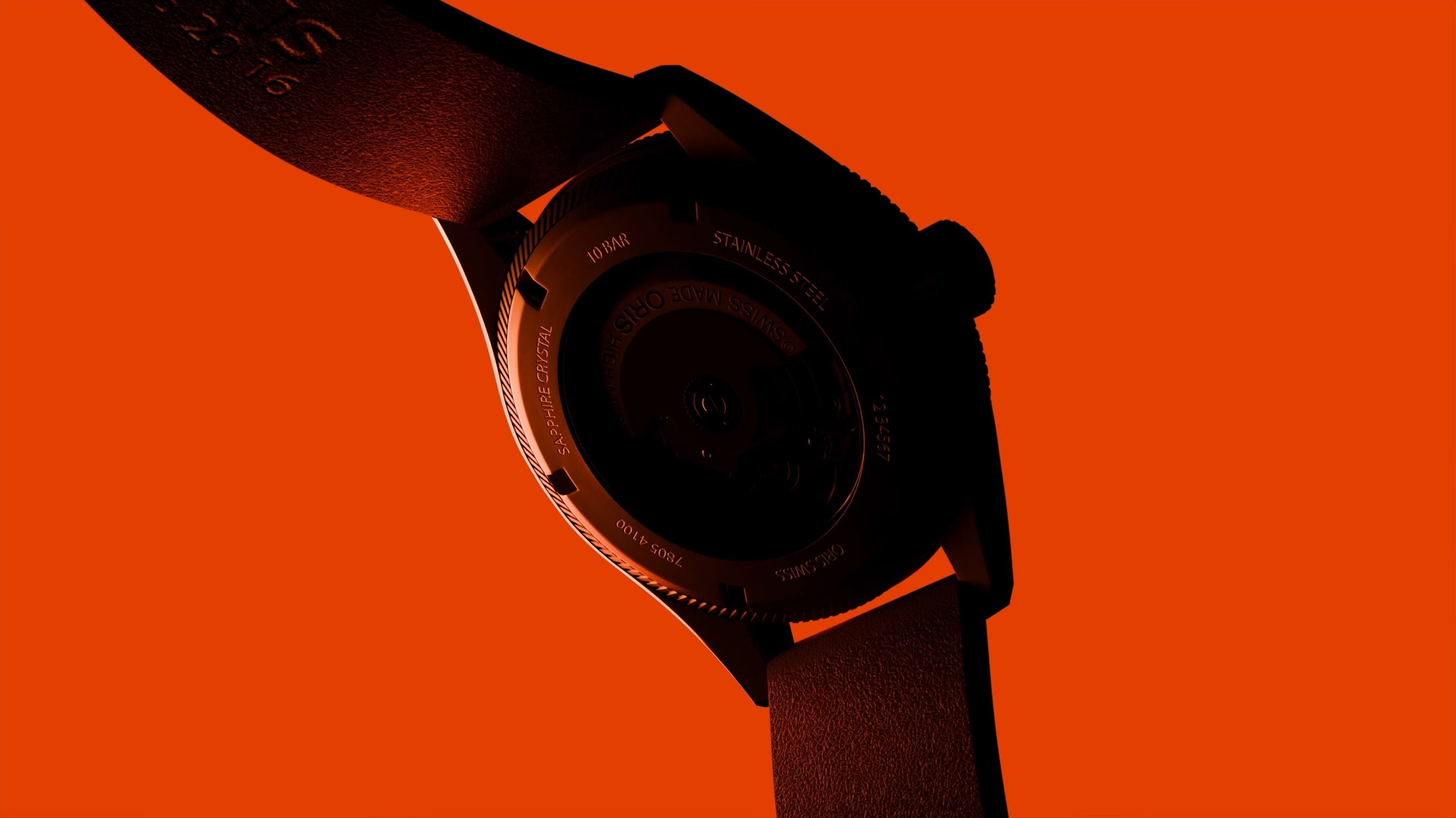 Dark wristwatch with leather strap on an orange background