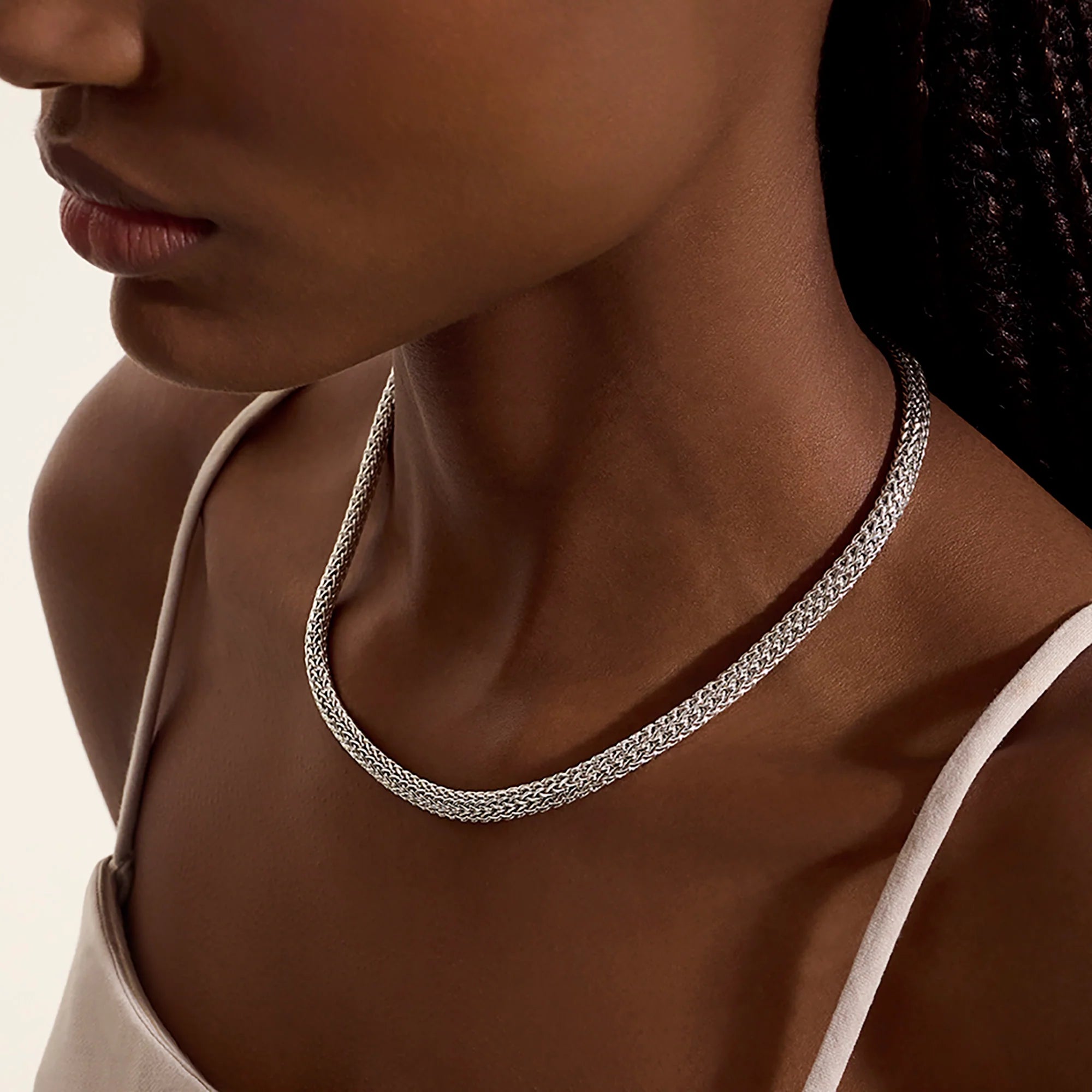 Close-up of a silver necklace on a person with a neutral background
