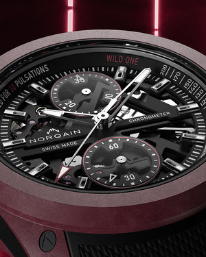Close-up of a Norqain watch with detailed face and red accents on a dark background