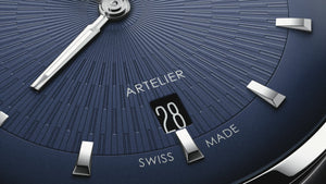 Close-up of a watch face with 'Artelier' branding and Swiss Made text.