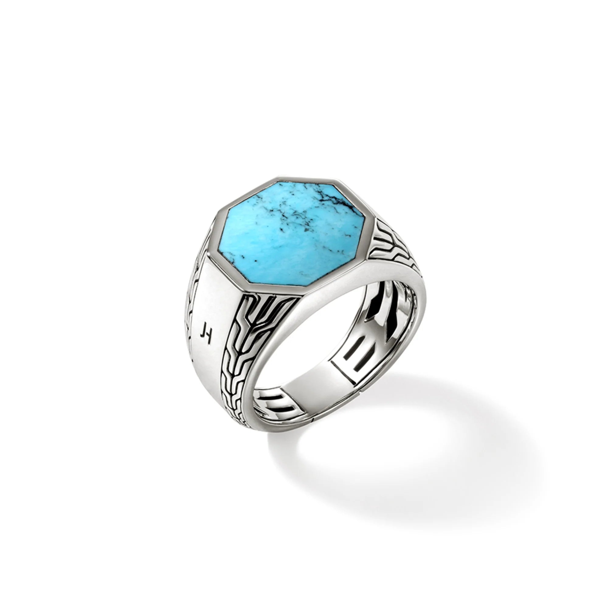 Angled view of Turquoise signet ring showing octagonal turquoise stone and carved sterling silver on white background