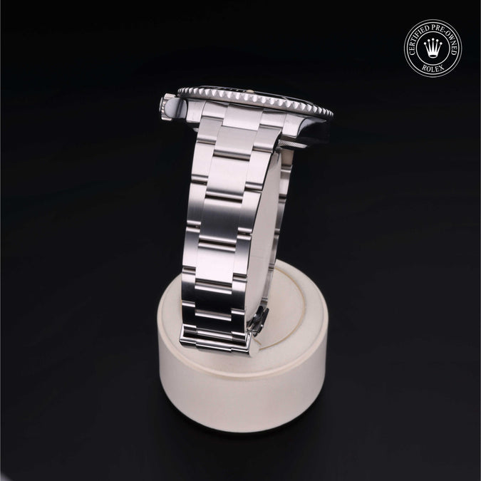 Rolex Submariner Date stainless steel bracelet and caseback on white display stand; badge reads CERTIFIED PRE-OWNED ROLEX