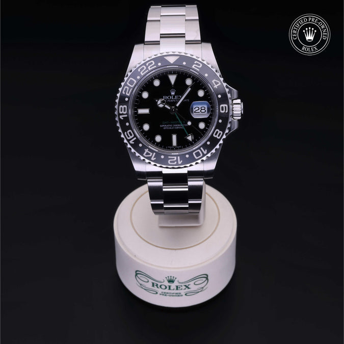 Silver Rolex watch on a white stand with a black background