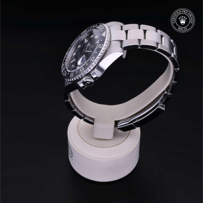 Silver watch on a white stand with a dark background