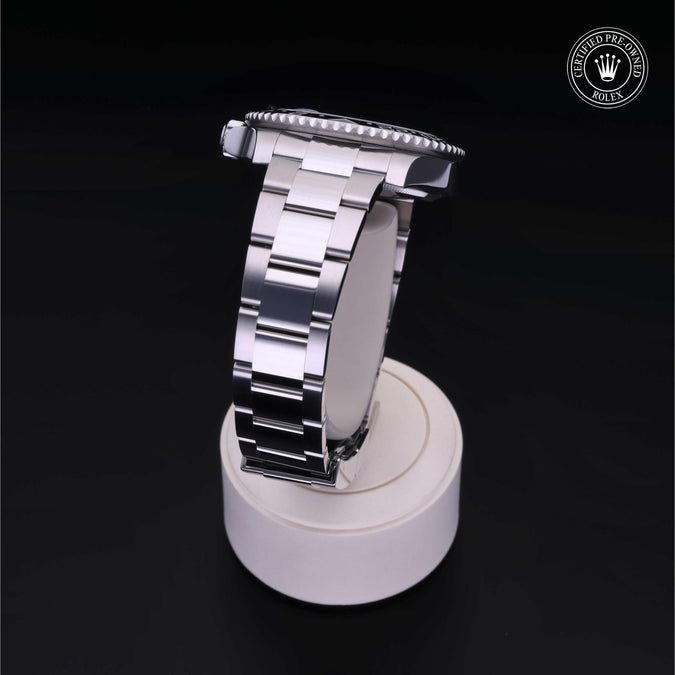 Silver watch strap on a white stand with a dark background