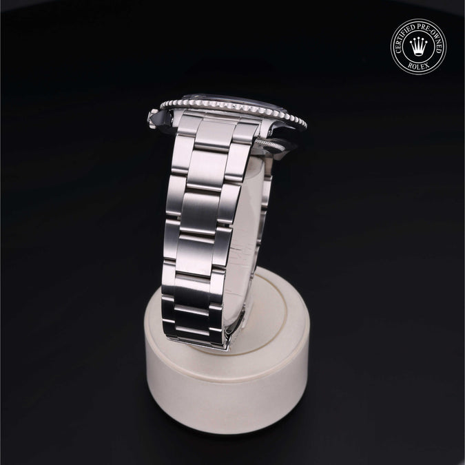 Silver watch on a white stand with a dark background