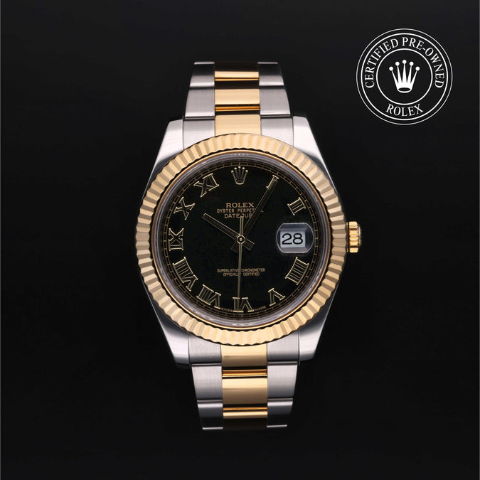 Rolex watch with black dial on a white stand against a dark background