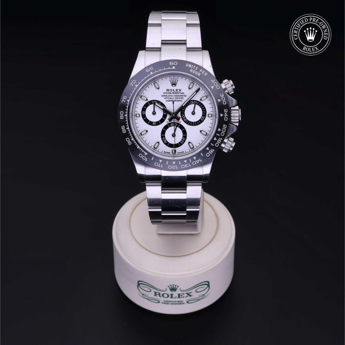 Silver Rolex with certified pre-owned logo with white dial and black markings sitting on a white stand on a black background
