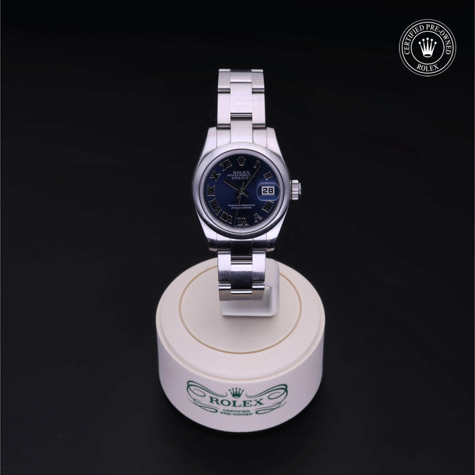 Silver watch on a white stand with a dark background