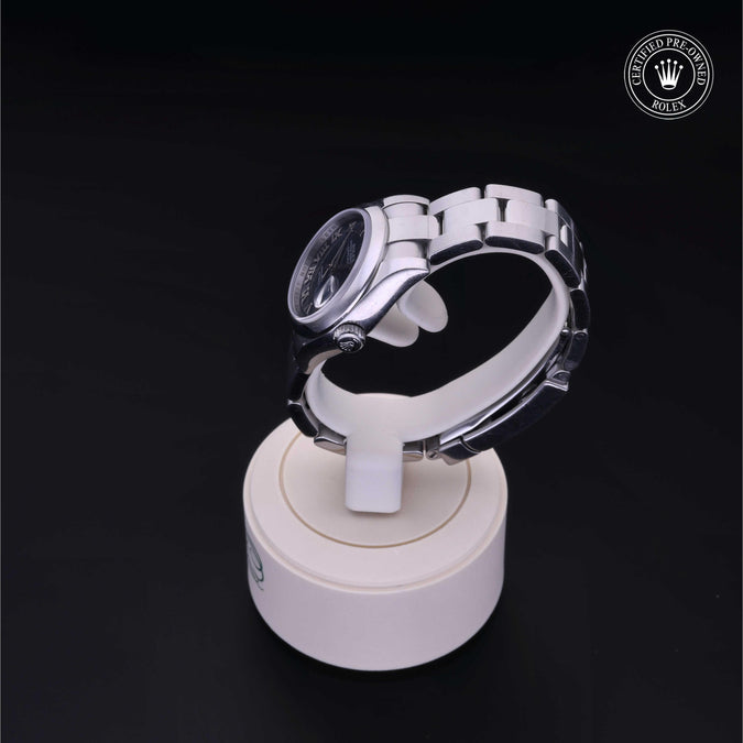 Silver ring on a white stand against a black background with a visible brand logo.