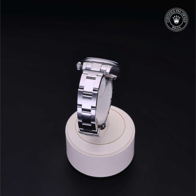 Silver watch on a white stand with a dark background