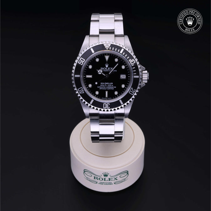 Silver Rolex watch on a white stand with a black background