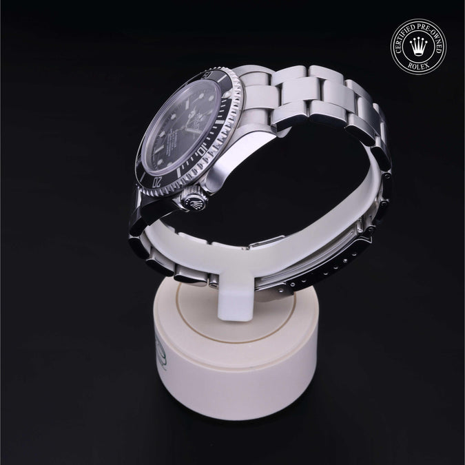 Silver watch on a white stand against a black background with a visible brand logo.