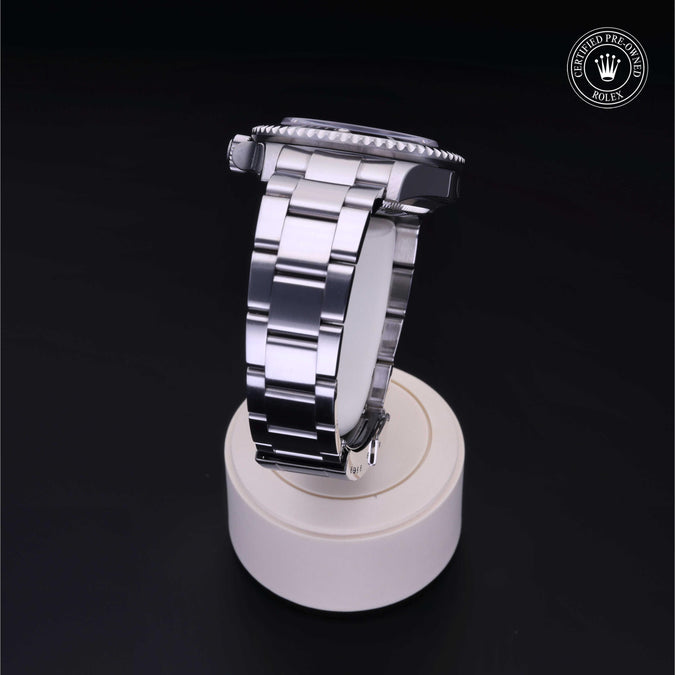 Silver watch on a white stand with a dark background