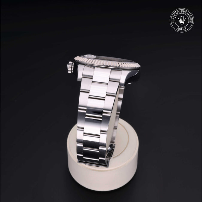 Silver watch on a white stand with a dark background