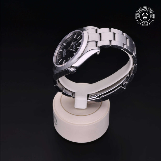 Silver watch on a white stand with a dark background