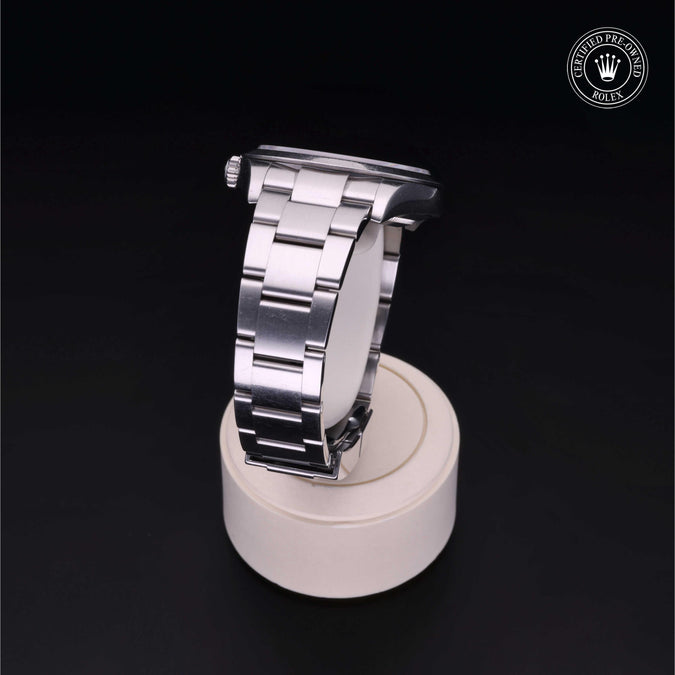 Silver watch band on a white stand with a dark background