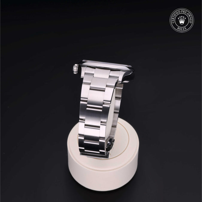 Silver watch strap on a white stand with a dark background
