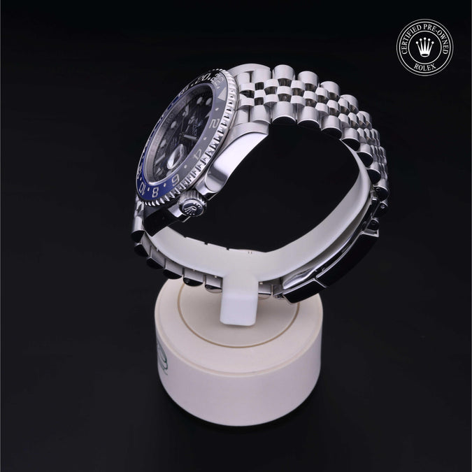 Angled view of Rolex GMT‑Master II showing black dial, blue-and-black bezel and jubilee steel bracelet on a white display stand