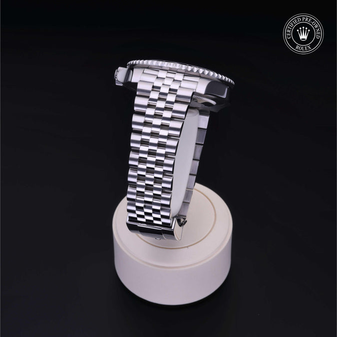 Side view of GMT-Master II watch showcasing stainless steel Jubilee bracelet and case profile on a white stand with black background