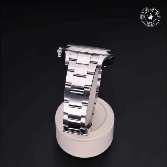 Silver watch on a white stand with a dark background