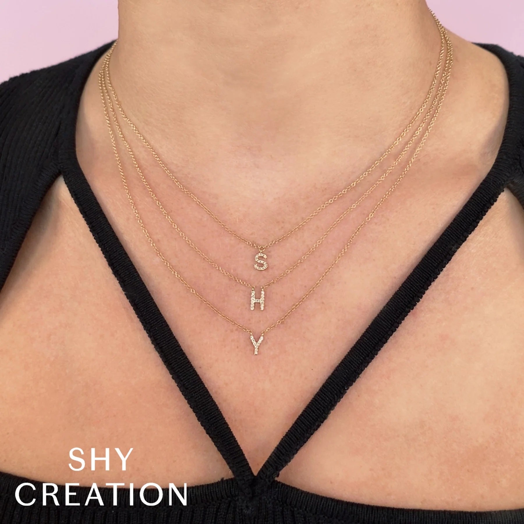 Three layered gold necklaces with diamond initials S H Y; text 'SHY CREATION' in lower-left.