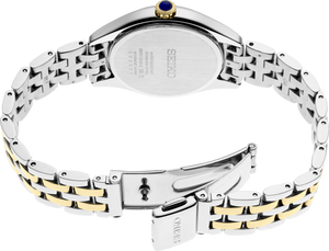 The back view of a Seiko women's watch featuring a two-tone stainless steel and gold link bracelet with a small blue accent jewel on the crown.