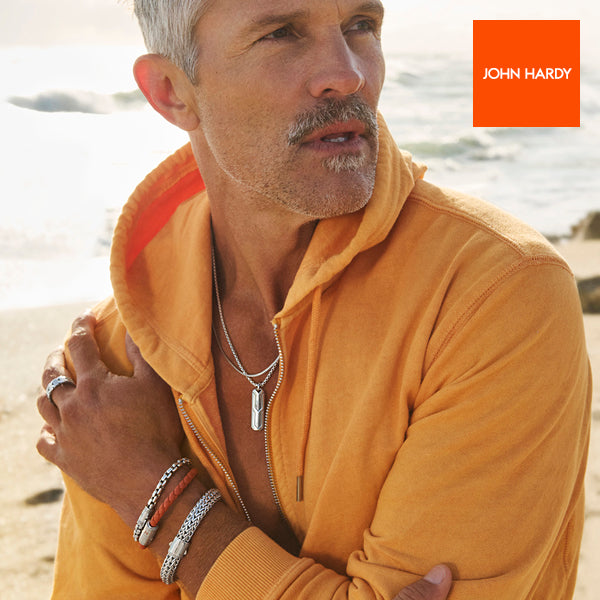 Male model on beach wearing necklaces and bracelets; JOHN HARDY logo in corner