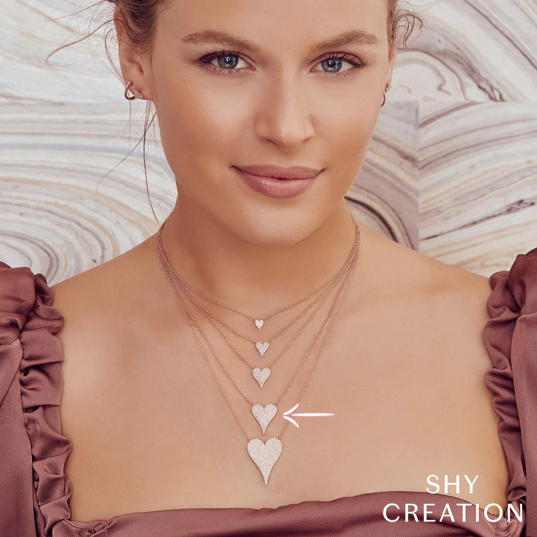 Model wearing four layered heart-pendant necklaces; arrow points to the third glitter heart. SHY CREATION
