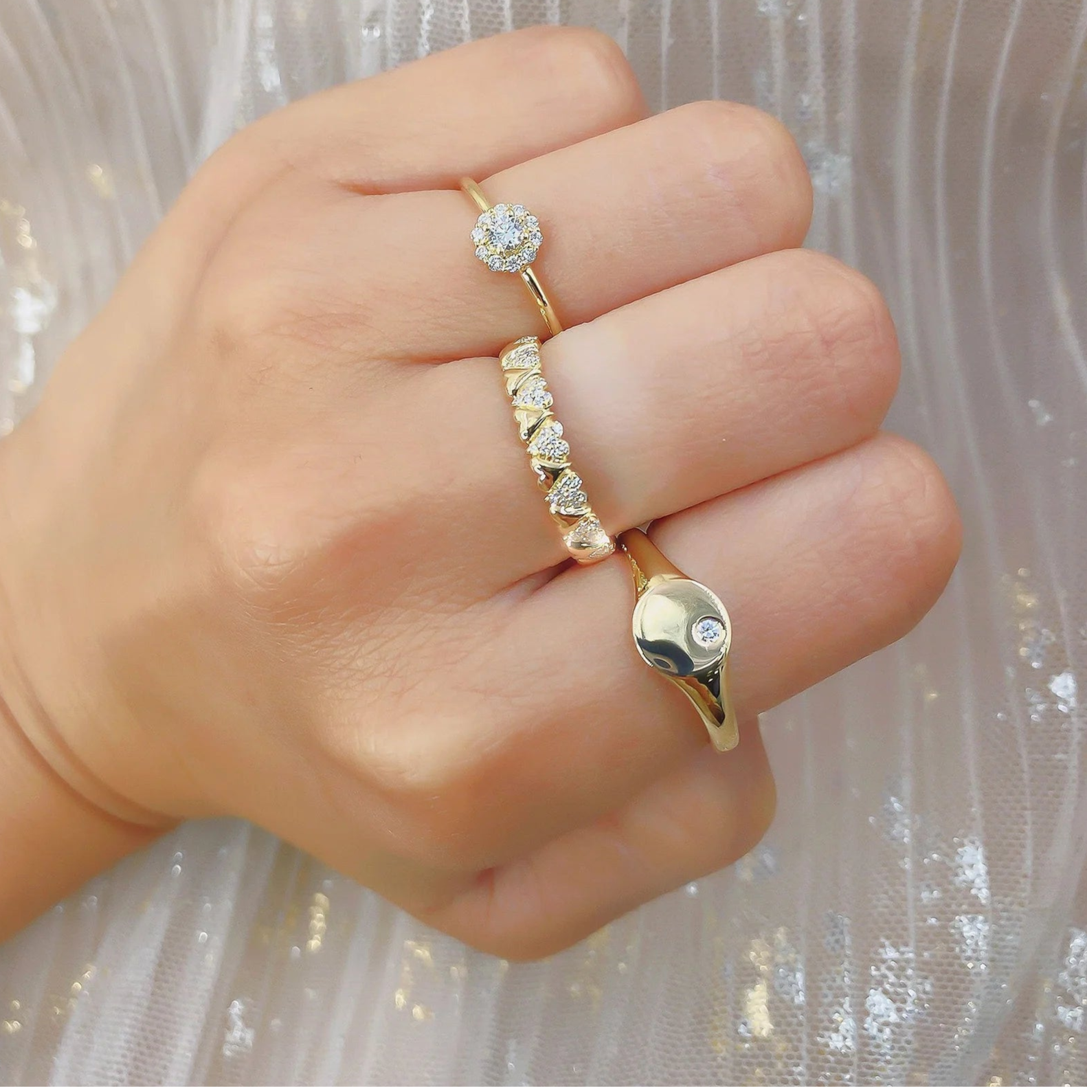 Angled view of 14K yellow gold signet ring with 0.03ctw offset diamond stacked with two diamond bands on a hand