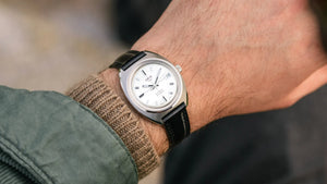 Close-up of a wrist wearing a silver watch with a black strap.
