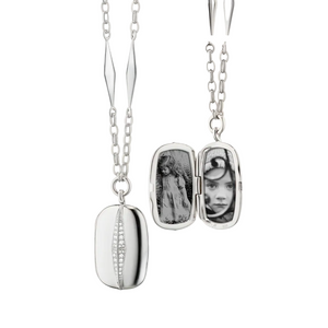 Silver locket necklace with white sapphires that holds 2 images on a white background