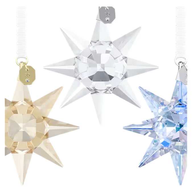 close up of 3 star ornaments in brown, blue and clear crystals with white ribbon on a white background